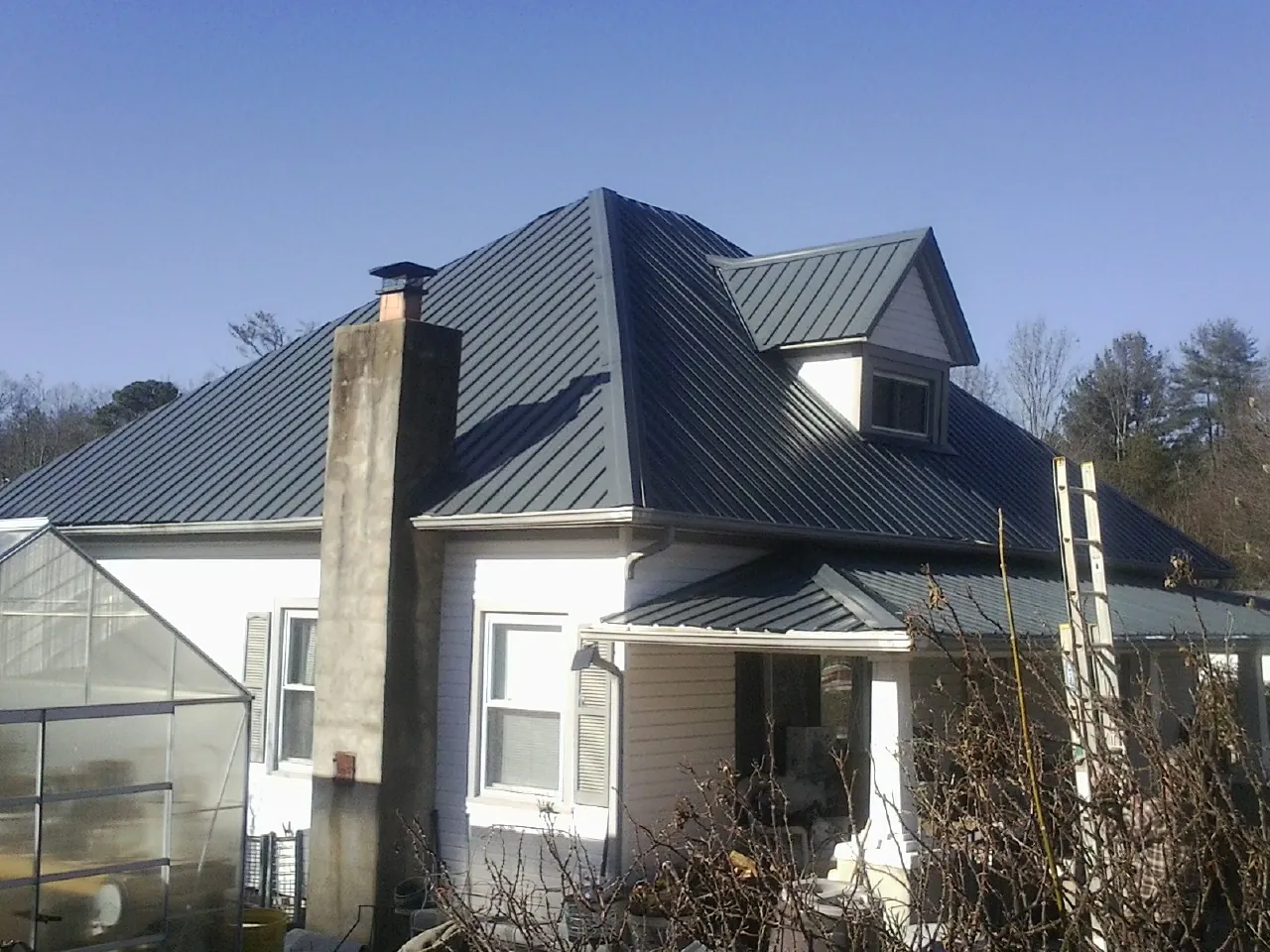 Dark blue standing seam metal roof on a white farmhouse with dormer — Slate & Tile Roof Repair by Roofing Brothers in Bobtown