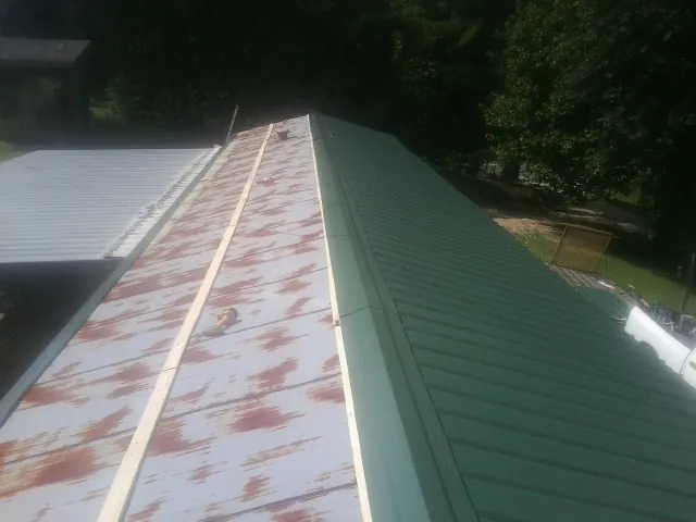 Old rusted panels beside newly installed green metal roofing — Wind Damage Roof Repair by Roofing Brothers in Bobtown