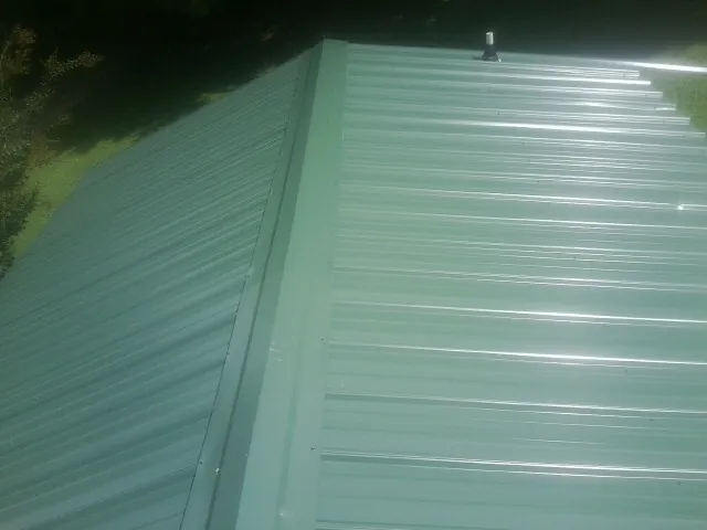 New green metal panels meeting at the ridge of a roof — Flat Roof Repair work by our crew in Bobtown