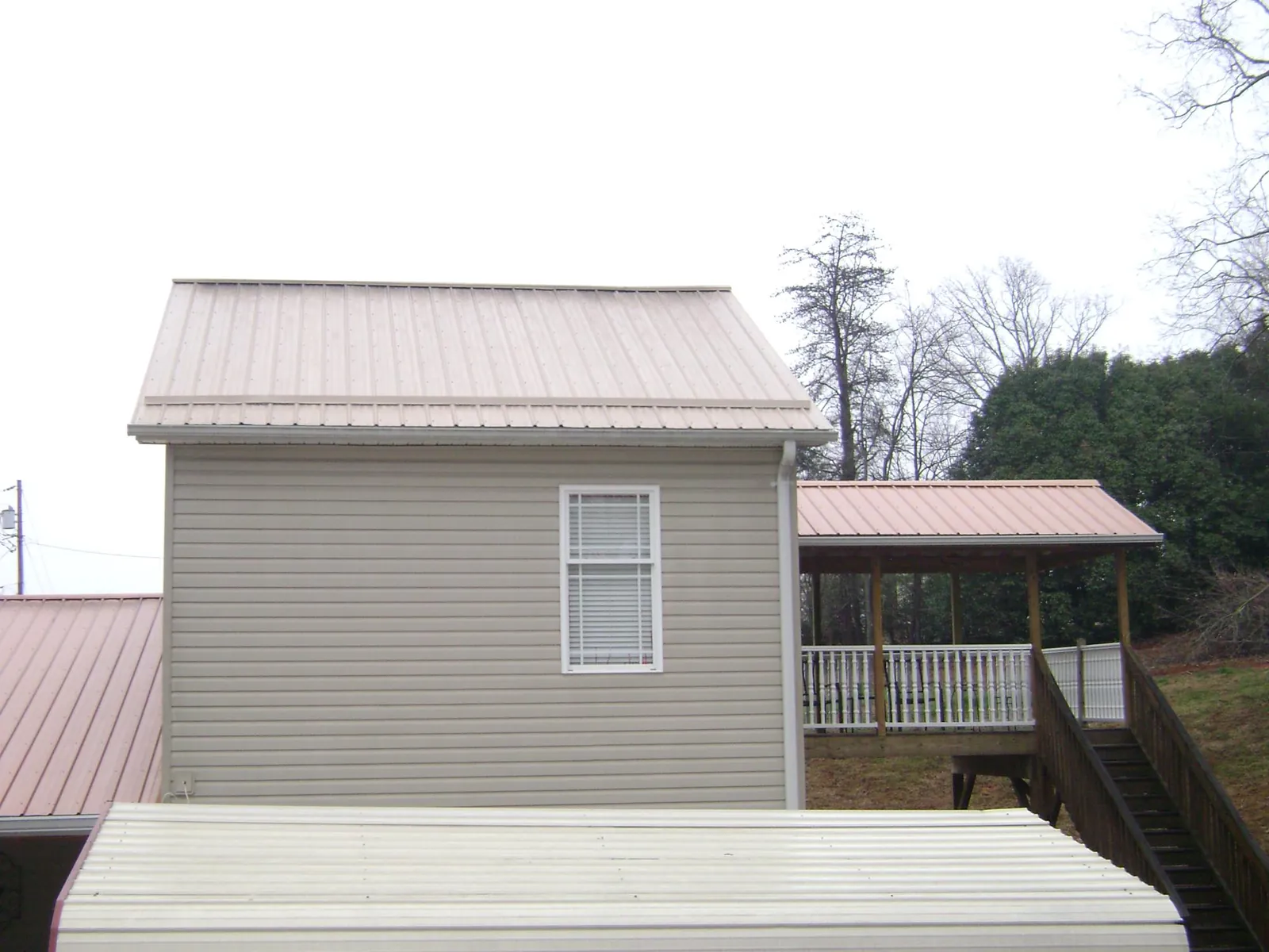 Tan metal roofs on a two story addition and attached porch, from a Roof Replacement job in Bobtown
