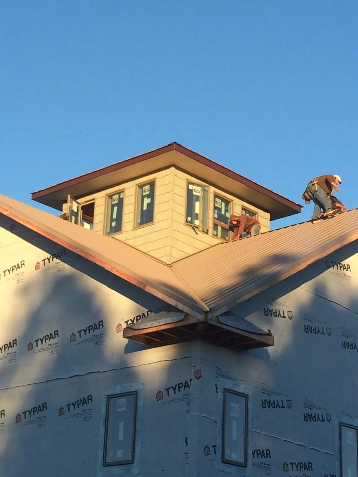 Roofers working around a rooftop cupola on a new metal roof at sunset — Roof Waterproofing in Bobtown by Roofing Brothers
